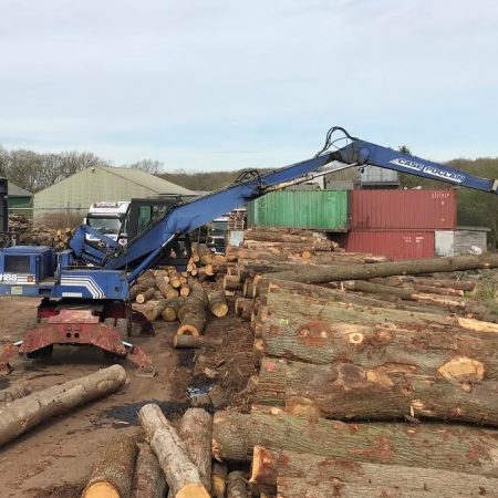 Large grabbing digger grabbing large pieces of oak beams in our outdoor facility loading onto our delivery lorry